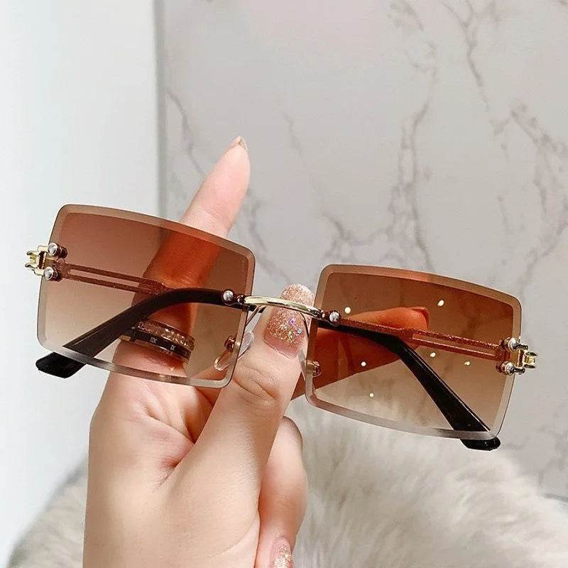 Sunglass Lover brown gradient rectangular rimless sunglasses for men with gold temples held in hand