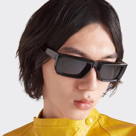 Black hip hop rectangle sunglasses worn by a person with medium length hair and a yellow jacket