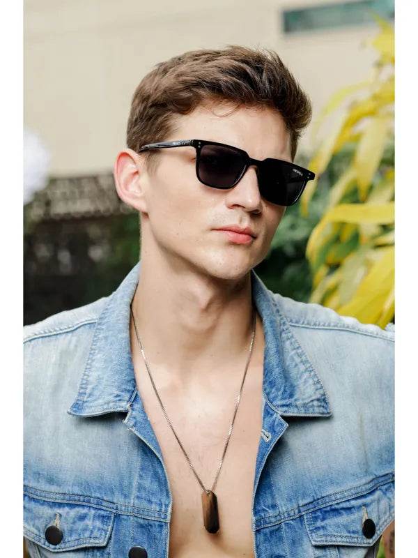 Young man wearing small black rectangle sunglasses with denim jacket modeled by Sunglass Lover